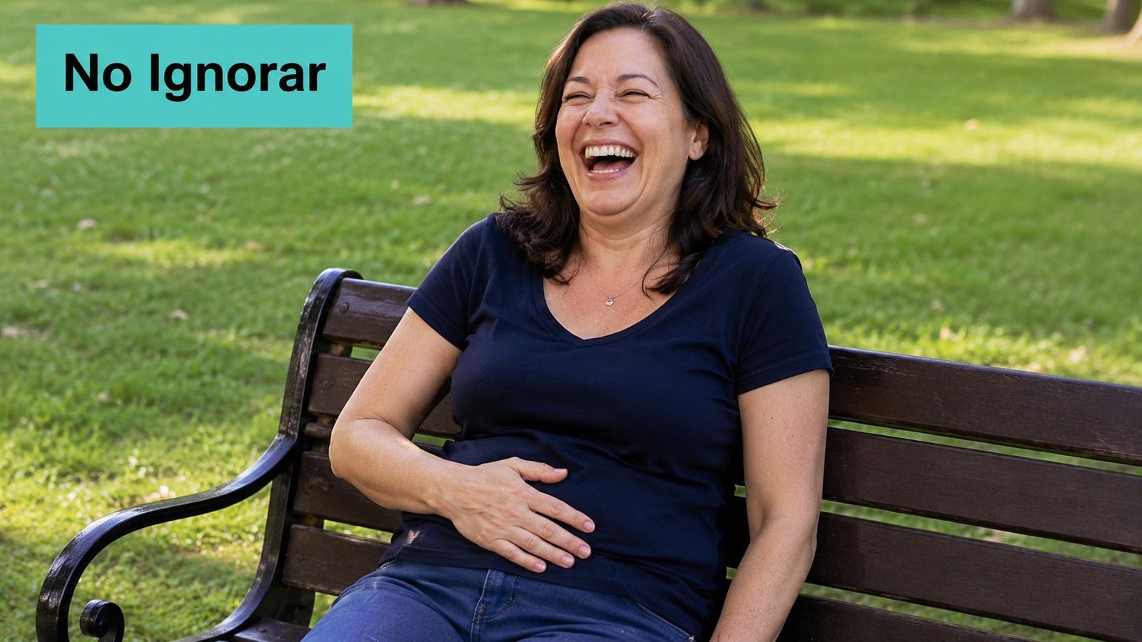 Una mujer feliz riéndose a carcajadas sentada en un banco de parque al aire libre.